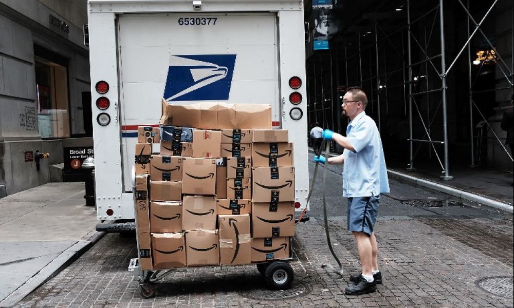 Trabajador del Servicio Postal de Estados Unidos entrega paquetes de Amazon.